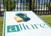 Thumbnail 44 of 48 - Cornhole board on lawn near pool and clubhouse at Allure Apartments, Whiteland, 46184