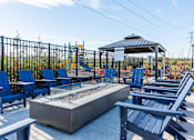 Thumbnail 15 of 29 - A gazebo is surrounded by blue chairs and a fire pit at The Warren Apartments, Jeffersonville, IN