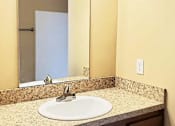 Thumbnail 6 of 10 - A bathroom sink with a mirror above it.