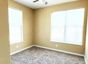 Thumbnail 8 of 10 - A room with a carpeted floor and two windows.