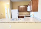Thumbnail 3 of 10 - A kitchen with a white refrigerator and brown cabinets.