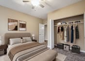 Thumbnail 4 of 7 - A bedroom with a large bed and a closet with clothes hanging.
