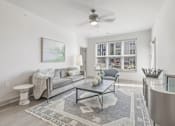Thumbnail 2 of 29 - A living room with a grey couch, a coffee table, and a ceiling fan at The Warren Apartments, Jeffersonville, IN