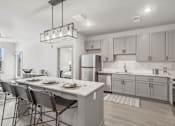 Thumbnail 4 of 29 - A modern kitchen with a dining table set for four at The Warren Apartments, Jeffersonville, IN
