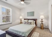 Thumbnail 7 of 29 - A bedroom with a bed, two lamps, and a painting on the wall at The Warren Apartments, Jeffersonville, IN