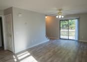 Thumbnail 16 of 23 - an empty living room with a sliding glass door and a ceiling fan