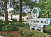 Thumbnail 1 of 19 - a sign for cypresswood apartments in front of trees and flowers
