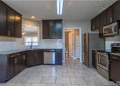 Thumbnail 2 of 18 - a kitchen with dark cabinets and a tile floor