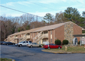 Thumbnail 5 of 13 - a large brick building with a stone chimney and a parking lot in front of it