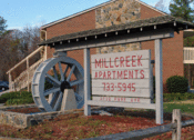 Thumbnail 4 of 13 - a sign for mill creek apartments with a water wheel