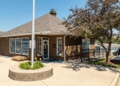 Thumbnail 11 of 23 - a small brown building with a flagpole in front of it