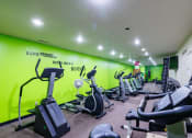 Thumbnail 14 of 23 - a gym with various exercise equipment on the floor and a green wall