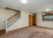 Thumbnail 18 of 23 - an empty living room with a staircase and a door to a kitchen