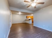Thumbnail 2 of 6 - an empty living room with a ceiling fan and a kitchen in the background
