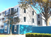 Thumbnail 14 of 15 - a white and blue apartment building with trees in front of it