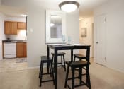 Thumbnail 5 of 15 - a dining area with a table and chairs and a kitchen in the background