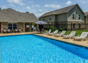 Thumbnail 3 of 14 - a swimming pool with chaise lounges and umbrellas in front of a house