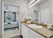 Thumbnail 10 of 25 - a bathroom with a sink and a mirror and a door to a bedroom