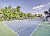 Thumbnail 29 of 32 - a tennis court with a fenced in area and trees