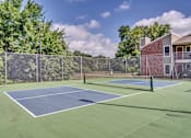 Thumbnail 32 of 32 - two tennis courts with a house and trees in the background