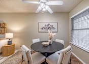 Thumbnail 16 of 31 - Dining room with round table and upholstered chairs at Highland Park Apartments, Fort Worth, Texas