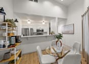Thumbnail 4 of 32 - A modern kitchen with a glass table and white chairs.