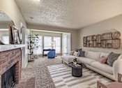 Thumbnail 4 of 31 - Living room with brick fireplace and woven wall art at Highland Park Apartments, Fort Worth, Texas