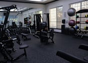 Thumbnail 4 of 29 - Fitness center with strength training equipment and weights at Clearwater Creek Apartments, Richardson, Texas