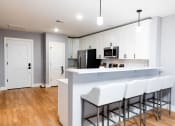 Thumbnail 10 of 106 - a kitchen with white cabinets and a white counter top with three stools in front of it