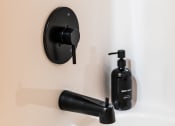 Thumbnail 32 of 106 - a bathroom with a black sink faucet and black soap dispenser