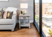 Thumbnail 16 of 106 - a living room with a gray couch and a table with a lamp and a large window