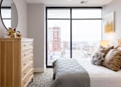 Thumbnail 89 of 106 - A bedroom with a large bed and a view of the city.