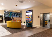 Thumbnail 38 of 106 - a lobby of a hotel with a yellow couch and chairs and a vending machine
