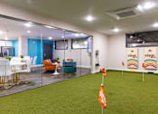 Thumbnail 75 of 106 - a room with an indoor putting green and a conference room with glass walls