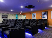 Thumbnail 72 of 106 - a cinema room with a row of black leather chairs and a projector screen