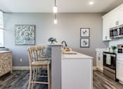 Thumbnail 3 of 33 - A kitchen with a white island and wooden chairs.