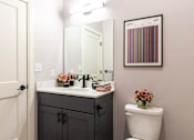 Thumbnail 28 of 38 - A bathroom with a white toilet and a sink with a mirror above it.