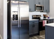 Thumbnail 24 of 38 - A kitchen with a stainless steel refrigerator and cabinets.