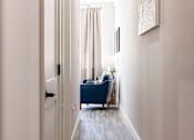Thumbnail 18 of 38 - A hallway with a blue couch and a painting on the wall.