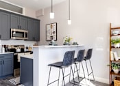 Thumbnail 2 of 38 - A kitchen with a white island and black barstools.