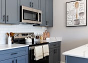 Thumbnail 1 of 38 - A kitchen with a white counter top and a picture of a whiskey glass and a spoon on the wall.