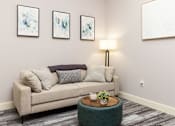 Thumbnail 9 of 38 - A living room with a couch, a table, and three paintings on the wall.