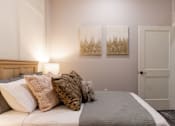 Thumbnail 34 of 38 - A bedroom with a bed, two pillows, a lamp, and two paintings on the wall.