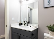 Thumbnail 14 of 38 - A bathroom with a sink, mirror, and toilet.