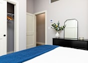 Thumbnail 16 of 38 - A bedroom with a blue bedspread and a black dresser.