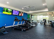 Thumbnail 77 of 84 - A gym with treadmills, exercise bikes, and television screens.