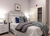 Thumbnail 6 of 84 - A bedroom with a bed, nightstand, and a picture on the wall.