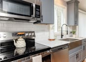 Thumbnail 2 of 53 - A modern kitchen with a black stove top and a black microwave above it.