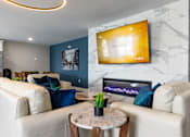 Thumbnail 23 of 50 - A living room with a white couch, a coffee table, and a flat screen TV mounted on the wall.