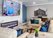Thumbnail 22 of 50 - A living room with a fireplace and a television on the wall.